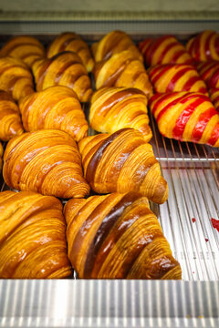 French raspberry croissant with fresh strawberries, featuring crisp golden layers and glossy red berry filling, displayed at a pastry shop