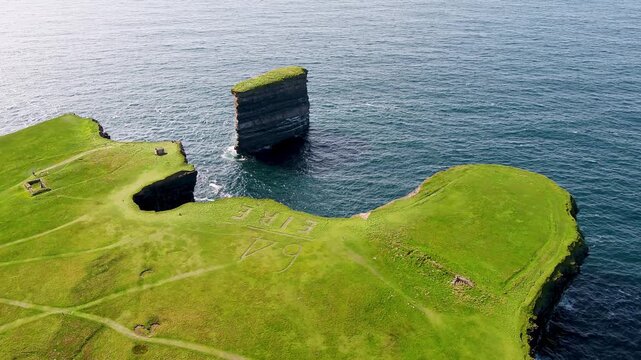 Aerial view of the iconic Dun Briste sea stack rising from the Atlantic Ocean near the grassy cliffs of Ballycastle, County Mayo, Ireland.