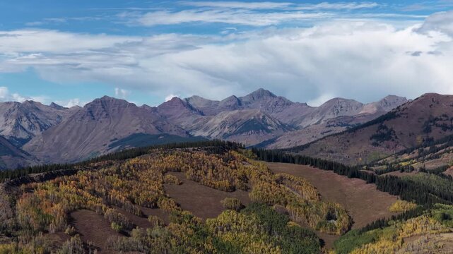 Aerial of Rocky Mountain range and autumn forest with colorful fall foliage in Gunnison National Forest in Crested Bute Colorado
