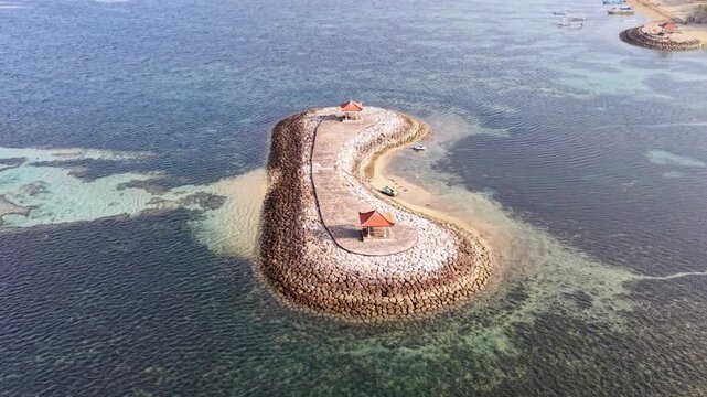 Aerial drone view of breakwater barrier island with traditional gazebos in clear blue ocean water