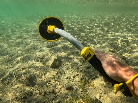 RUMMU, ESTONIA - SEPTEMBER 02, 2026: Underwater POV view of a handheld PI-iKing metal detector pinpointing searching for lost items at the bottom of clear water in Rummu quarry lake.