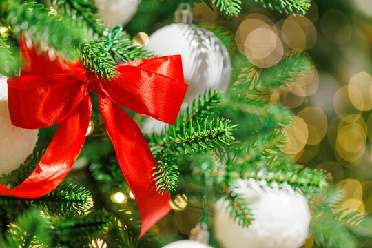Red bow on Christmas tree with festive golden lights