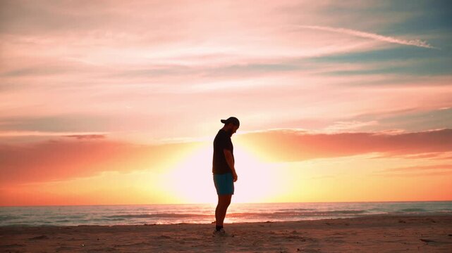 Meditating man breathing deeply on the beach during a stunning sunrise, finding inner peace and tranquility while connecting with nature's spiritual energy and finding wellness