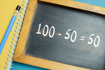 Obraz premium Chalkboard with phrase simple 100-50=50 math equation on wooden desk. For basic subtraction and primary school education