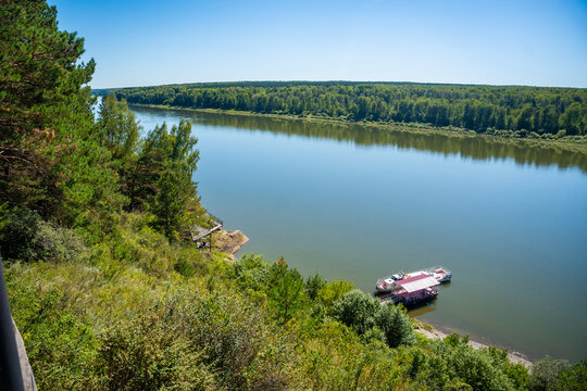 Scenic view of Tom River in Yashkinsky District near Tomskaya Pisanitsa, Siberia. Forested riverbanks and calm water form natural summer landscape