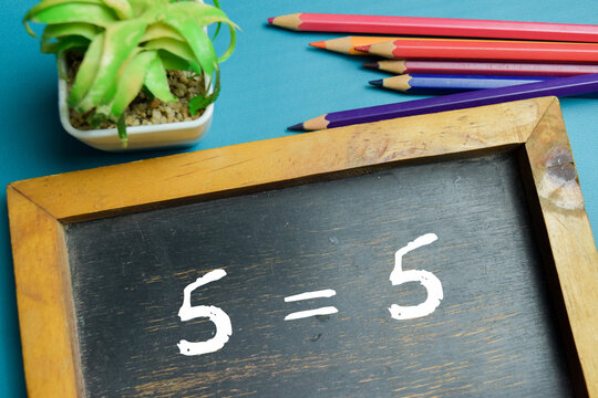 Chalkboard with phrase 5 equality equation on wooden desk. For balance, accuracy and comparison