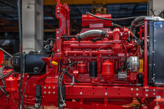 Close-up of powerful red tractor engine assembly on factory production line. Complex mechanical systems, agricultural or construction machinery production.