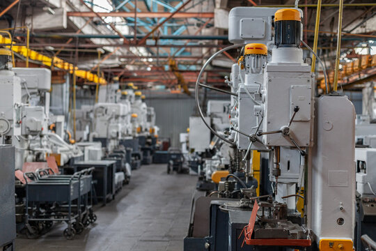 Rows of heavy industrial drilling machines inside large tractor manufacturing plant. Precision machinery, industrial development, manufacturing technology, global supply chain.