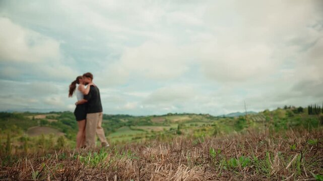 Romantic young couple running and hugging on a scenic hill in tuscany, italy, enjoying their love and freedom together during a summer vacation in the beautiful countryside