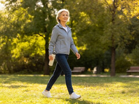 Senior Woman Walking in Park with Water Bottle