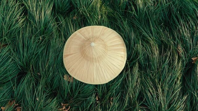 Traditional woven bamboo hat resting on lush green grass in Hangzhou
