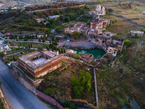 Aerial view of the historic Katas Raj Temple Complex featuring ancient stone structures, a sacred pond, and surrounding hilly landscape in Katas, Punjab, Pakistan.