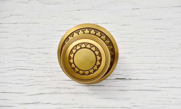 round gold door knob with flourishes on a white door