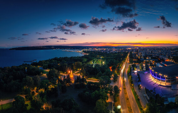 Panoramic aerial view of Varna coastline with Palace of Culture and Sports, Sea Garden, and city lights at dusk