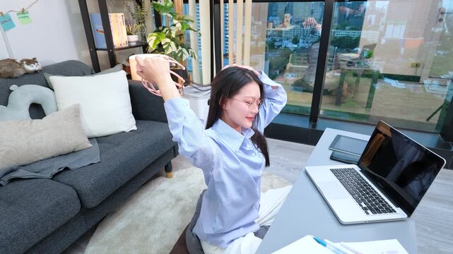 Asian Woman Massaging Head with Scalp Massager While Working from Home
