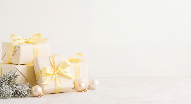 Arrangement of beautifully wrapped white gift boxes adorned with elegant gold satin ribbons on a light surface creating a sophisticated seasonal present concept.