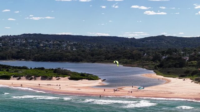 Aerial view of Long Reef Beach featuring a kite surfer on the sandy shore, a calm lagoon, and coastal hills in Northern Beaches Council, New South Wales, Australia.