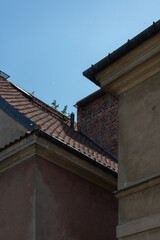 Ancient residential architecture features historic tenement buildings with traditional clay tile roofs and a brick chimney. Old town urban heritage stands under a clear blue sky. © dimetradim