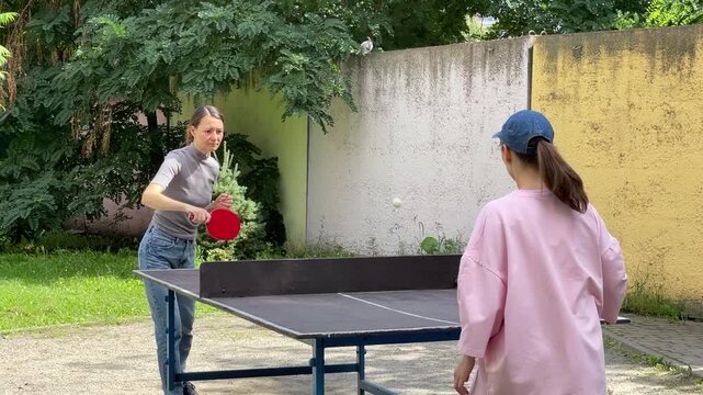 Outdoor sport - two Women Engage In Lively Table Tennis Game