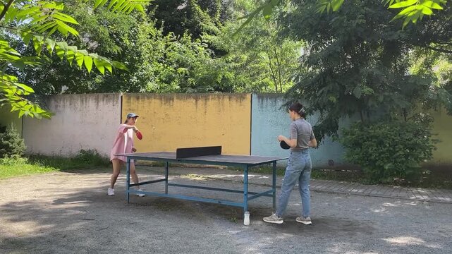 Outdoor sport - two Women Engage In Lively Table Tennis Game