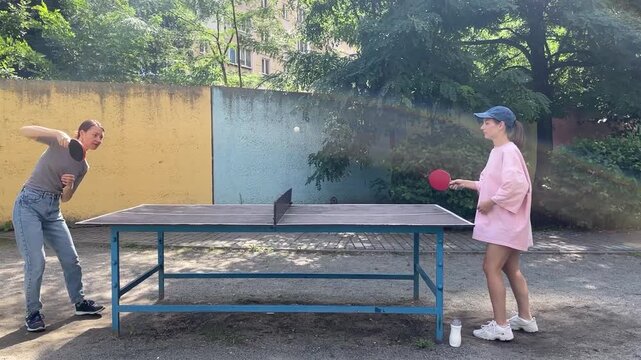 Outdoor sport - two Women Engage In Lively Table Tennis Game