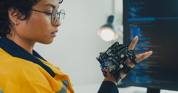 Close-up young Black female engineer coding AI robot arm in modern laboratory. Robotics, artificial intelligence, technology, stem, future, innovation, diversity, automation, machine learning concept.