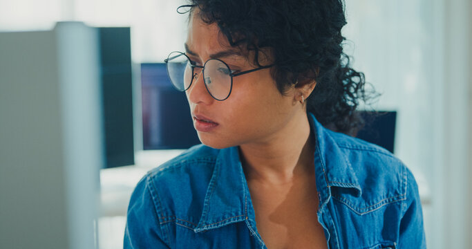 Close-up young professional African American female programmer coding AI software on screens in modern home office. Generative AI, machine learning, digital innovation, future technology concept.