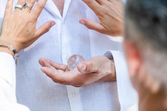 Hands gathered around a clear crystal during a spiritual meditation practice, representing focused intention, energetic connection, mindfulness, and emotional harmony.