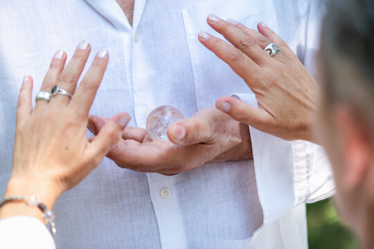 Alternative healing practitioner directing her hands toward a clear crystal during a guided spiritual healing session centered on mindfulness, energy flow, emotional balance, and connection.