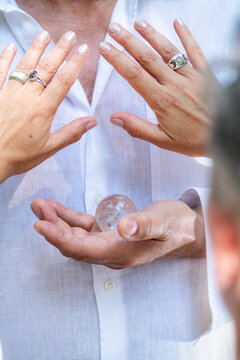 Close-up of multiple hands surrounding a clear crystal during guided meditation, symbolizing shared energy, spiritual connection, mindfulness, healing, and holistic balance.