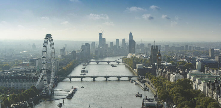 Aerial view of the London Eye and Big Ben along the River Thames with the city skyline and bridges in London, England, United Kingdom.