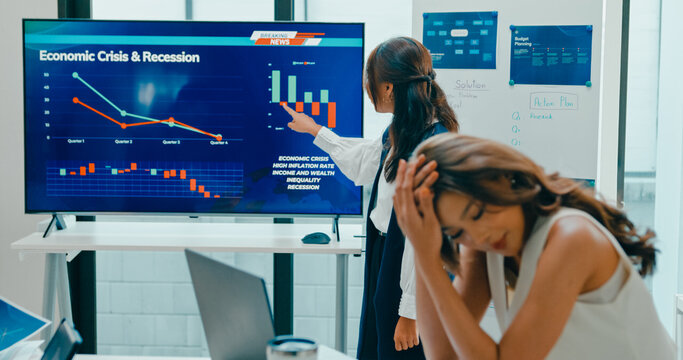 Group of Asian businesspeople work together leads business meeting uses presentation TV with revenue, profit or sale statistics in office. Financial generation z team brainstorm on e-Commerce project.