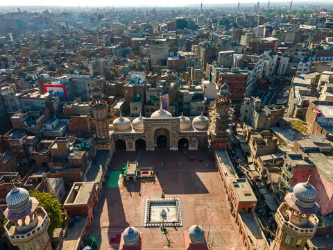Aerial view of Wazir Khan Mosque with its distinctive minarets, domes, and courtyard surrounded by the dense urban fabric of the old city in Lahore, Punjab, Pakistan.