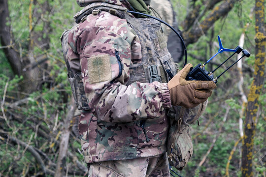 Ukrainian soldier holding drone controller with antennas in forest