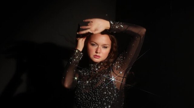 Woman with a lowered head at a dark wall. Slight movement blur, cold shadow and sparkling gown express solitude, fatigue and inner dialogue.