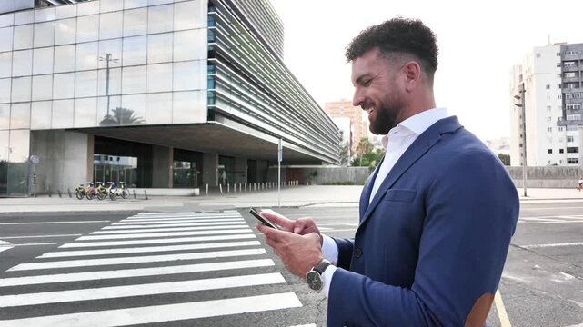 Smiling businessman holding a mobile phone while standing outdoors near an office building. Modern business, communication and urban professional lifestyle concept.