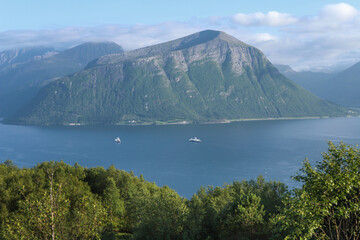 Obraz premium Beautiful norwegian fjord landscape with ferries operating at Solavagen pier. Storfjorden fjord with steep mountain slopes in the sunnmore region of Norway.