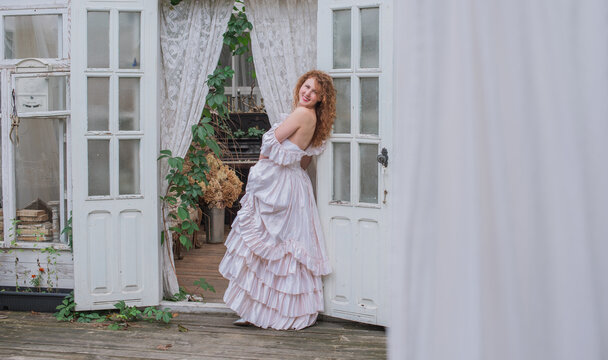 Romantic Victorian Woman in Pink Vintage Dress Sitting in Antique interior