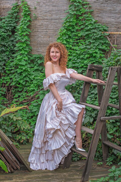Romantic Victorian Woman in Pink Vintage Dress Sitting in Antique interior