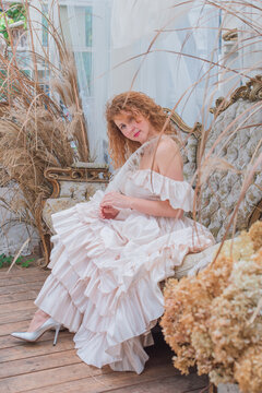 Romantic Victorian Woman in Pink Vintage Dress Sitting in Antique interior