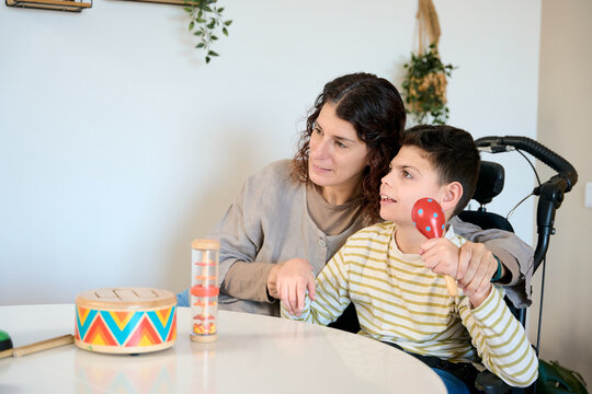 Mother assisting child with cerebral palsy during music therapy