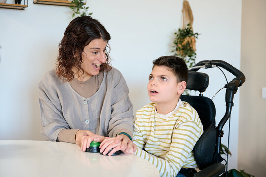 Therapist assisting boy with cerebral palsy using communication device