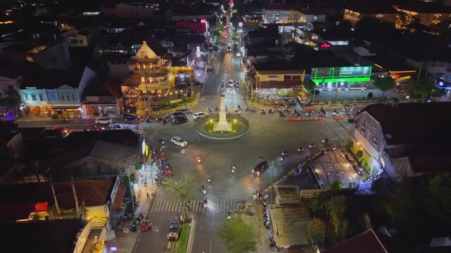 Aerial view of Tugu Yogyakarta Monument illuminated at night with busy traffic and city lights in Yogyakarta, Special Region of Yog, Indonesia.