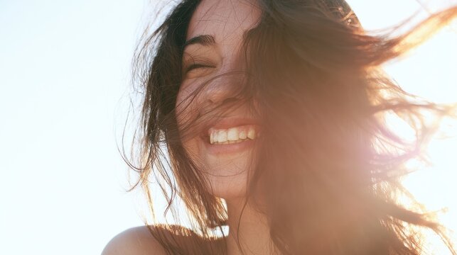 Smiling woman enjoying sunny beach day with flowing hair and bright sunlight