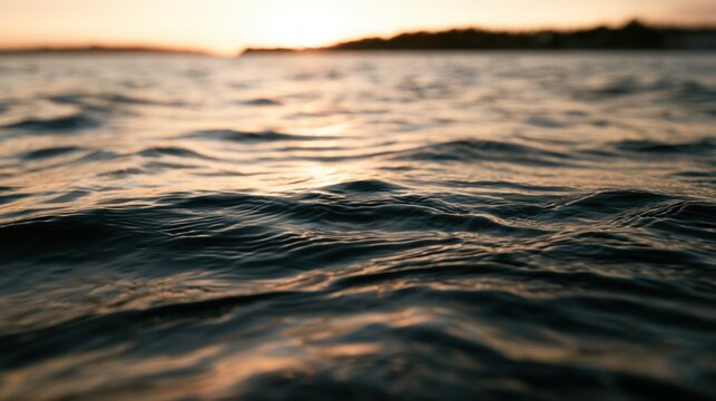 Sunset over the water with gentle waves and warm light reflecting on the surface