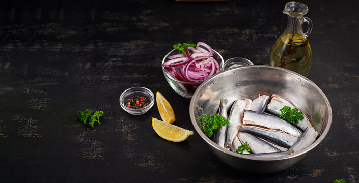 Fresh Sardines with Red Onion, Lemon and Olive Oil on Dark Background. Banner