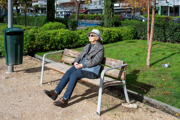 Senior woman relaxing on park bench enjoying sunshine