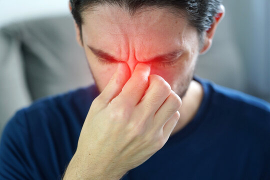Sinus headache (sinusitis) concept. Man with fingers pressing between the eyebrows with red highlight pain area.