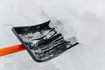 Naklejka premium snow shovel in snow, cleaning territory of snow, courtyard, path, garden, black and orange shovel, snowfall, atmospheric precipitation, bad weather conditions