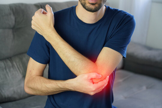 Lateral epicondylitis (tennis elbow). Unidentified man with opposite hand holding the outside of the elbow. Red highlight pain area.